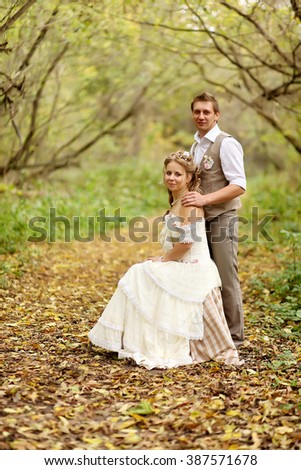 The bride and groom in a rustic style sitting at autumn forest.