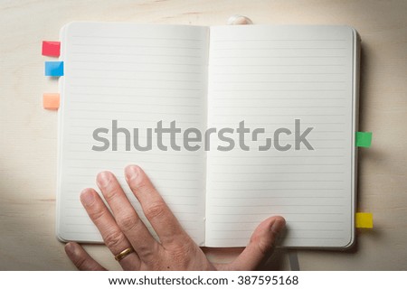 Male left hand touch at opened notebook with blank area for text or message on wood table in morning time with low key scene