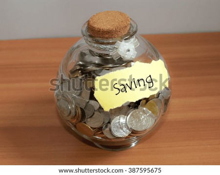 Coins in glass money jar with House label. Saving concept.
