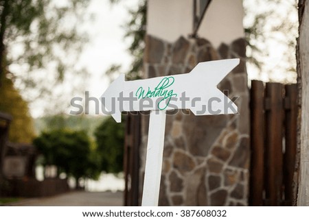 White wedding sign with green lettering, arrow shape