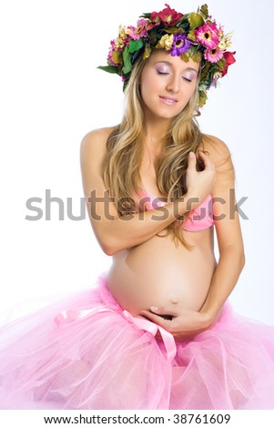 Beautiful young pregnant blonde girl in studio shot with flower wreath on white background