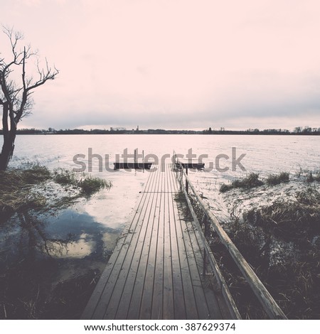 Reflections in the calm lake water with dramatic clouds and  with boardwalk- vintage effect