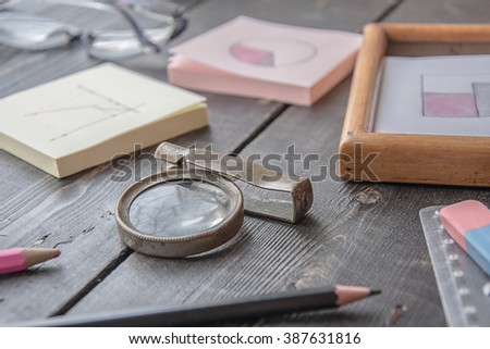 Business Desktop background, business graph paper, glasses, pencil, notebook, magnifying glass, eraser on a wood table background