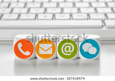 Letter dice in front of a keyboard - Contacting Royalty-Free Stock Photo #387658474