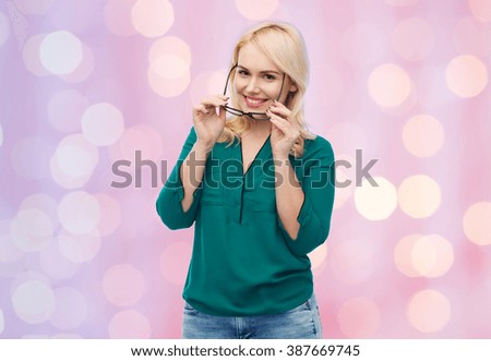vision, optics, education and people concept - smiling young woman with eyeglasses over pink holidays lights background