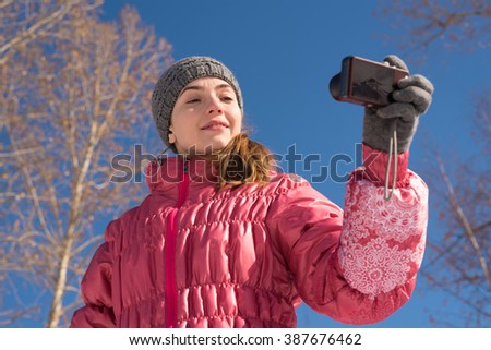 Woman in pink taking a selfie with a little point-and-shoot camera.