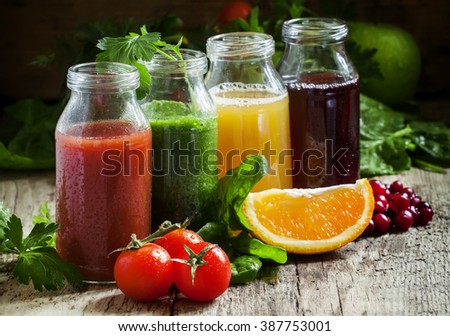 Bottles with fresh juices from fruits and vegetables on an old wooden background, selective focus
