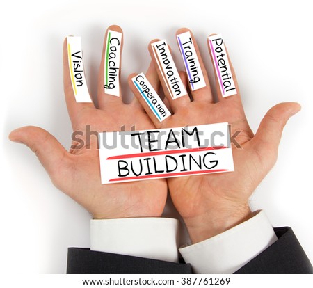 Photo of hands holding paper cards with TEAM BUILDING concept words