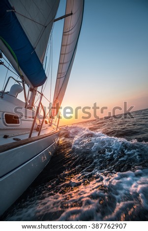 Sail boat moving in the open sea at sunset  Royalty-Free Stock Photo #387762907