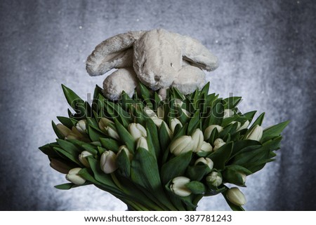 Plush rabbit with a bouquet of white tulips