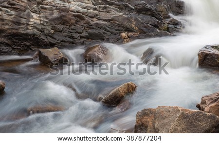 horizontal orientation color image, taken with a very slow shutter speed, to show the movement of water along a rocky creek in Colorado /  Beautiful, flowing Water