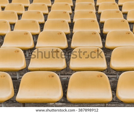 Rows of multilevel empty yellow plastic grandstand seats with number at an outdoor sport stadium in Singapore. Seamless pattern of outdoor stadium/arena chairs on main stand. Sport background, concept