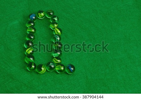 The letter Q made out of marbles on a green background