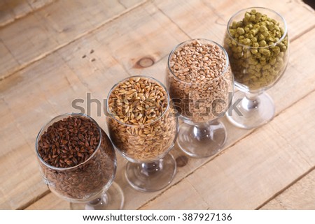 Glasses full of malts and hops over a wooden background Royalty-Free Stock Photo #387927136