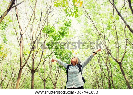 Beautiful young woman carrying backpack walking in forest stretch her hands happy with fresh air