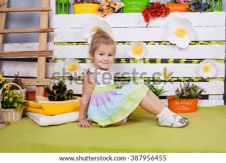 Sweet girl in a light dress in sandals sitting on a bright color background