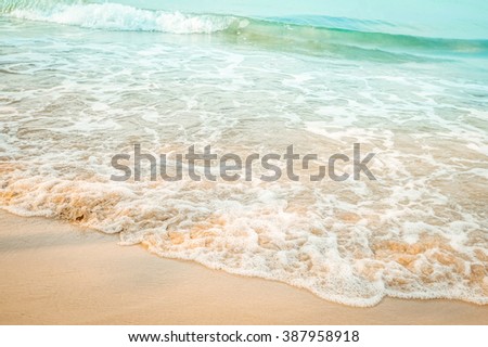 Sea water waves with bubbles on sand beach
