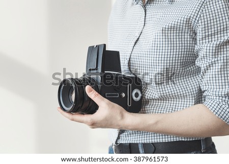 Hands of young woman holding film camera