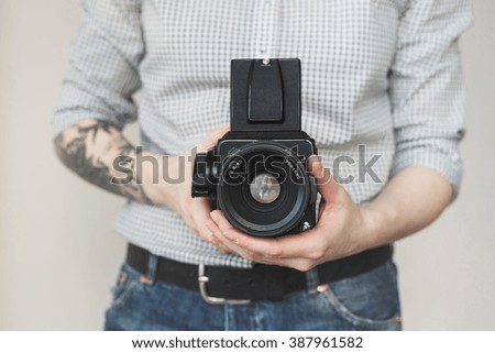 Tattooed hands of young woman holding film camera