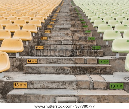 Rows of multilevel empty yellow and light green plastic grandstand seats with number at an outdoor sport stadium in Singapore. Seamless pattern of outdoor stadium/arena chairs on main stand.