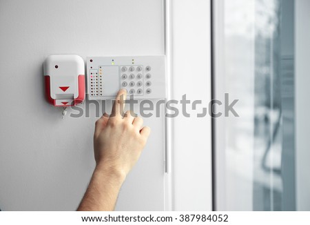 Security alarm keypad with male hand, closeup