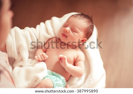 Small baby girl sleeping on mothers hands closeup. Top view. Woman holding infant girl. Motherhood.  Royalty-Free Stock Photo #387995890