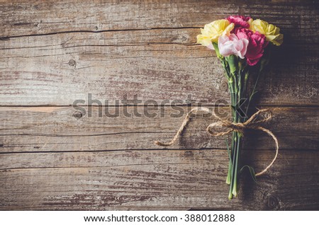 Carnation flowers on wooden table Royalty-Free Stock Photo #388012888