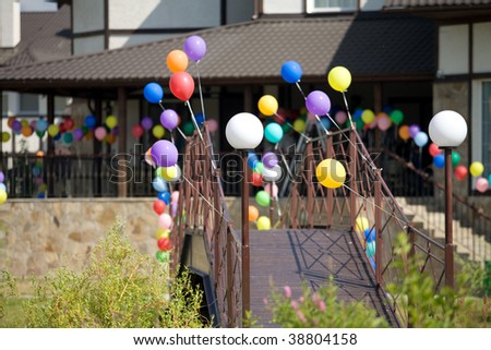 Colorful helium balloons at bridge that leads to house on background
