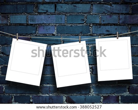 Close-up of three hanged square photo frames with pegs on blue brick wall background