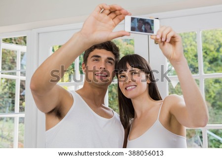 Young couple taking a selfie on mobile phone in living room