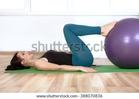 Girl doing exercises lying on the floor. She makes the press putting her foot on the gym ball. Concept: lifestyle, fitness, aerobics and health.