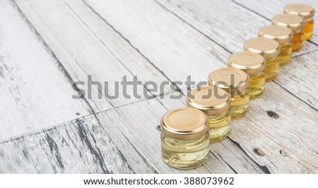 Different grades and colors of honey in glass jars over white background.