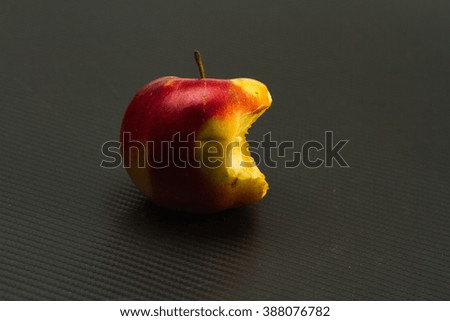 one half-eaten Apple on a carbon fiber background