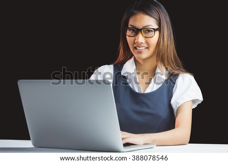 Smiling businesswoman using laptop on black background