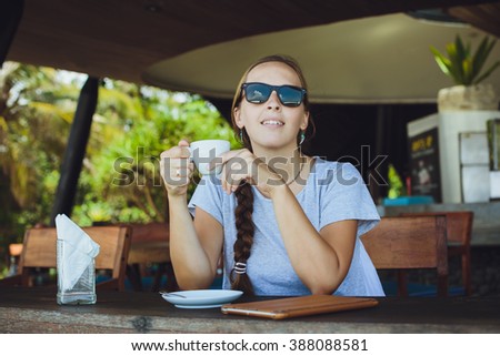 Young woman drinking coffee in the morning at restaurant  near the sea (soft focus on eyes).