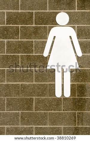A female washroom sign on a brick wall
