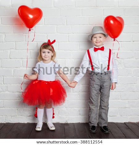 Little kids holding and picking up heart balloons. Valentine's Day and love concept, on white background