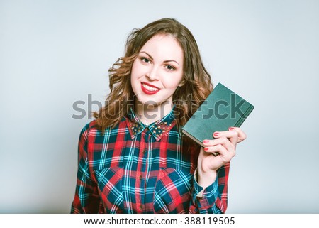 Portrait of a young woman smiling and holding a notepad, isolated on a gray background