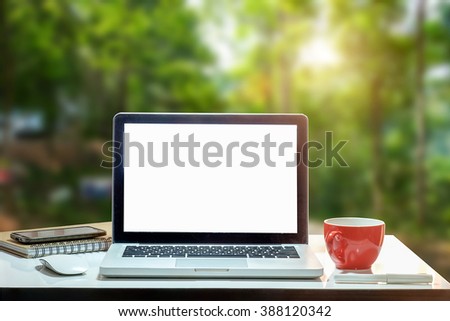 Front view of cup and laptop on table in Office park and blurred background of trees in the forest