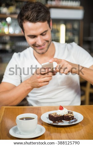 Handsome man taking a picture of his food in a pub
