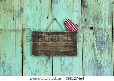Blank wood sign with rope heart hanging on antique rustic mint green wooden door; Valentine's Day and love concept background with painted copy space