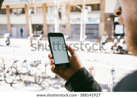 Closeup image of a man holding smart-phone and looking at blank white screen