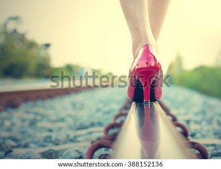Female legs in red high heels on the rail of the railway. (Vintage style)