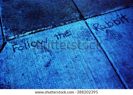 Dark sidewalk inscription, "follow the rabbit." The directions Alice followed before she fell down the Rabbit hole to Wonderland.