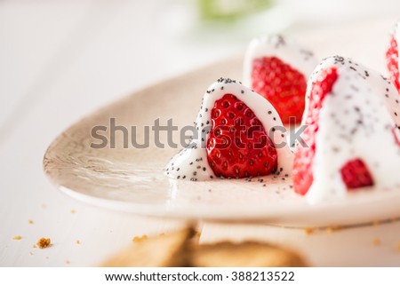 Fresh strawberries on a dish with yogurt and poppy seeds.