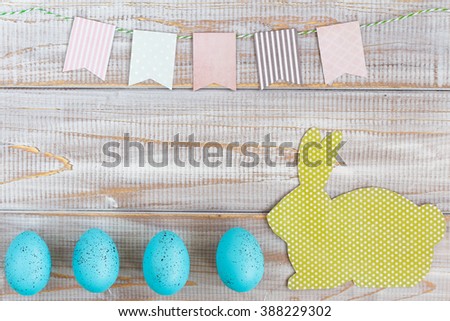 Pastel Easter background with colored eggs, easter bunny and flags. Top view