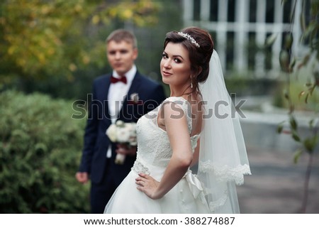 Beautiful stylish newlywed couple posing in botanic garden, glass structure background