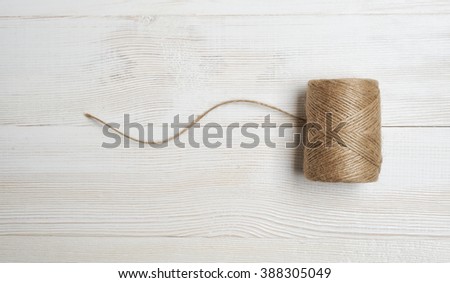 Spool of wool thread on a white wooden background. Top view desktop
