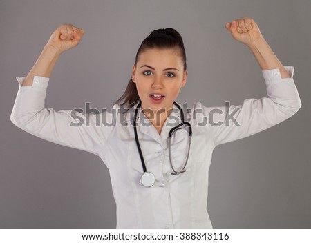 Nurse with stethoscope is showing how strong she is against of grey background