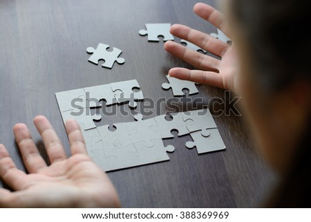 Female hands on a wooden office desk pick puzzle. Macro with blur and soft focus